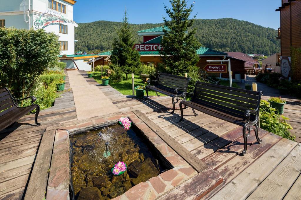 a park with two benches and a fountain with flowers at Krestovaya Pad in Listvyanka