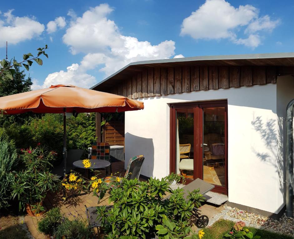 Ce petit cottage blanc est doté d'un parasol orange. dans l'établissement Ferienwohnung Graf Düne, à Karlshagen