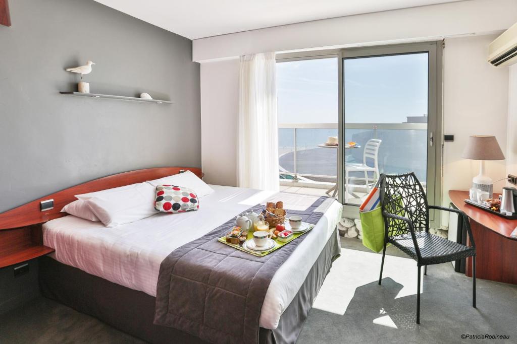 a hotel room with a bed with a tray of food on it at Kyriad Prestige Les Sables d'Olonne - Plage - Centre des Congrès in Les Sables-d'Olonne