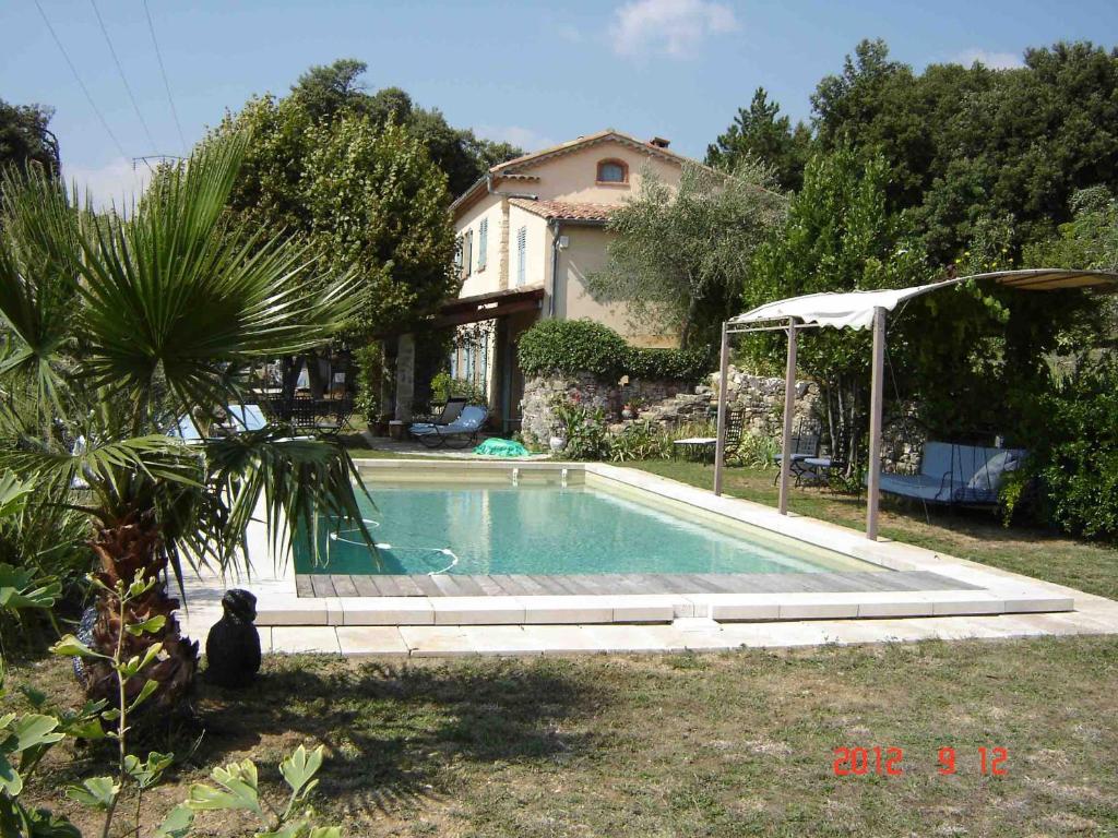 una piscina en un patio con sombrilla en Roubies, en Mons