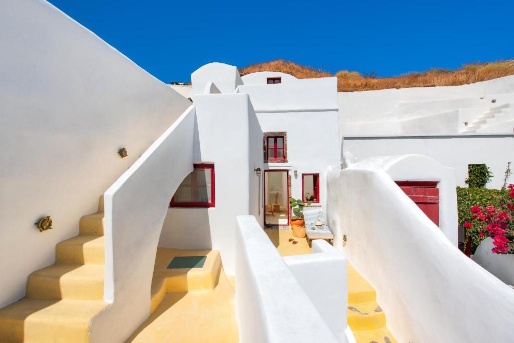 una casa bianca con scale bianche e fiori di Oikia Cave House a Éxo Goniá