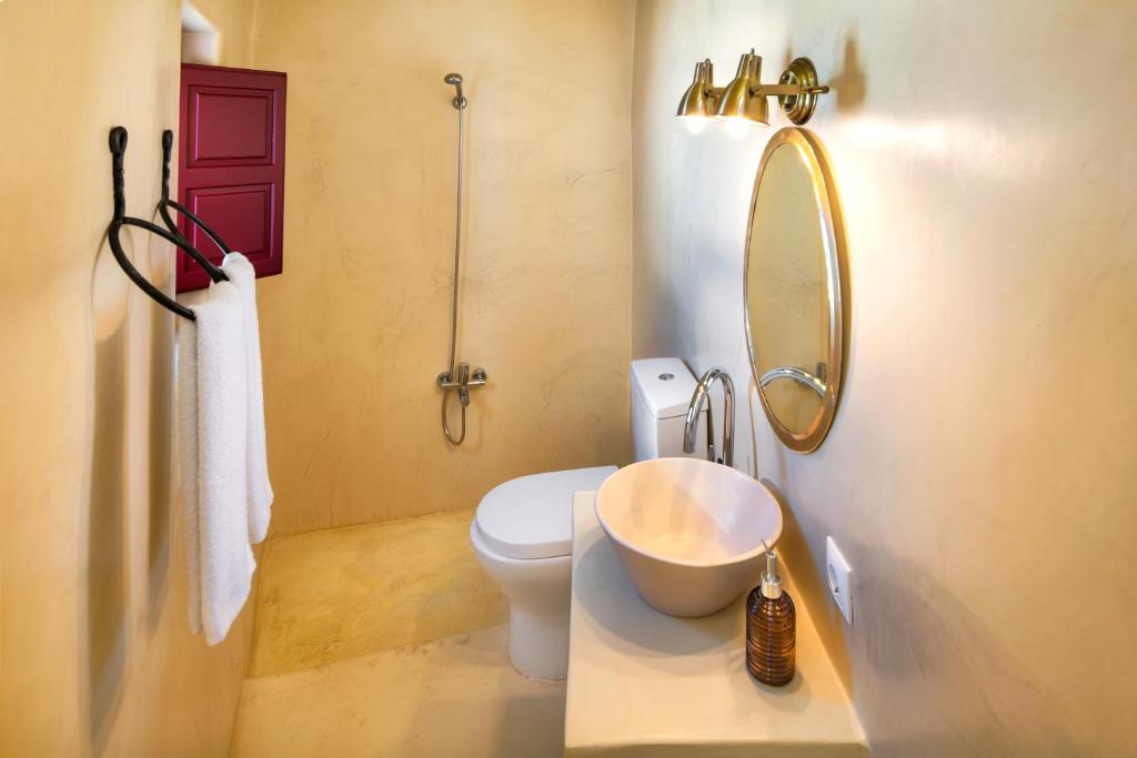 un bagno con un water, un lavandino e uno specchio di Oikia Cave House a Éxo Goniá