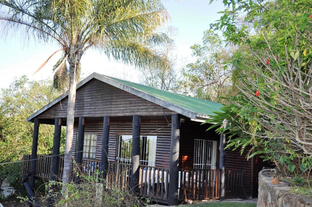 una pequeña casa de madera con un árbol delante en Impala Niezel Lodge & Guest House, en Hazyview