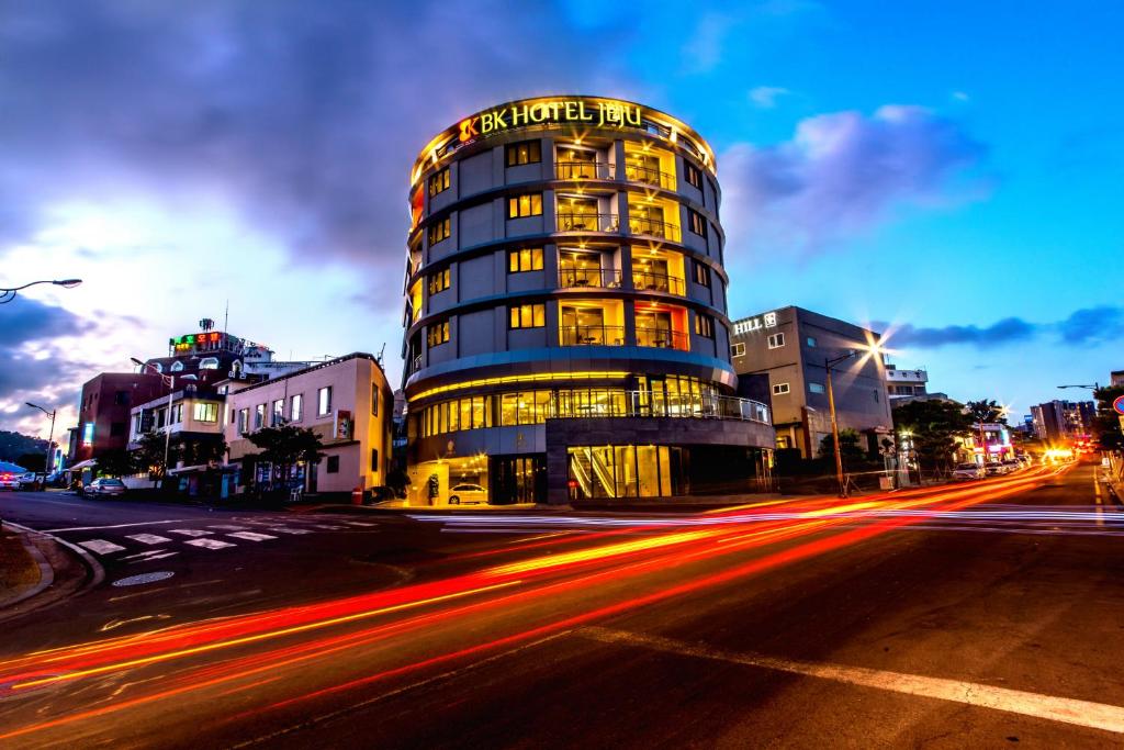 a tall building on a city street with cars at BK Hotel Jeju in Seogwipo