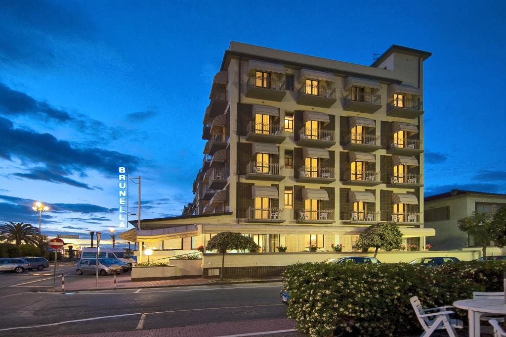 Un grand bâtiment avec des lumières allumées dans un parking dans l'établissement Hotel Brunella, à Lido di Camaiore