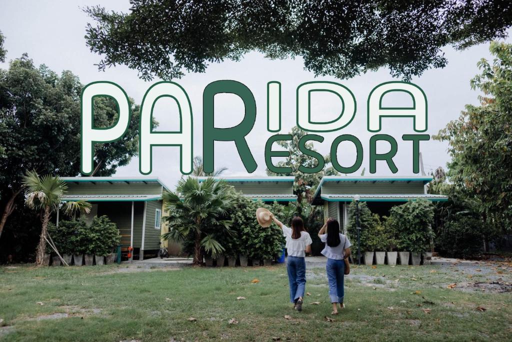 two women standing in front of a park sign at Parida Resort in Sing Buri