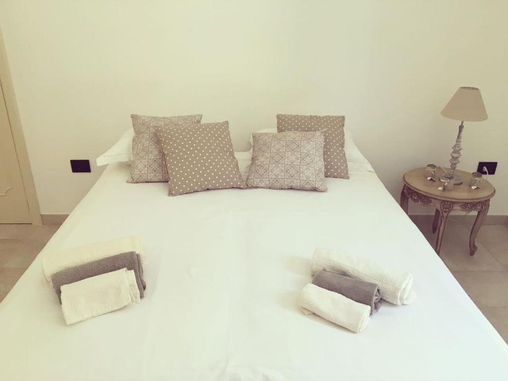 duże białe łóżko z poduszkami i stołem w obiekcie Monolocale Cora w mieście Corsano