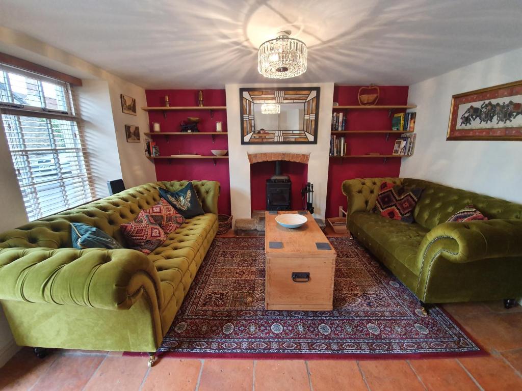 a living room with two green couches and a table at Fern Tree Cottage in Frome