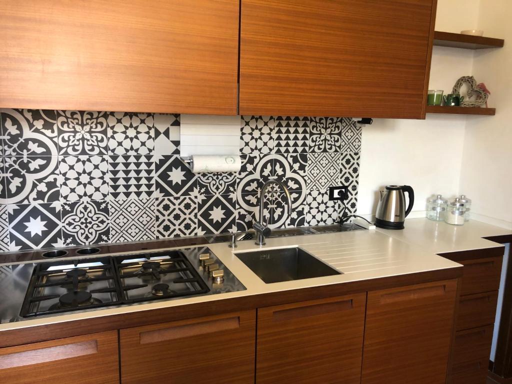 a kitchen with a sink and a black and white tile wall at CASA VARENNA in Capriate San Gervasio