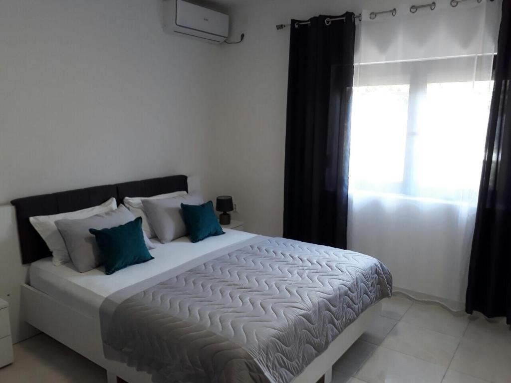 a bedroom with a bed with blue pillows and a window at Apartments Dionis in Kotor
