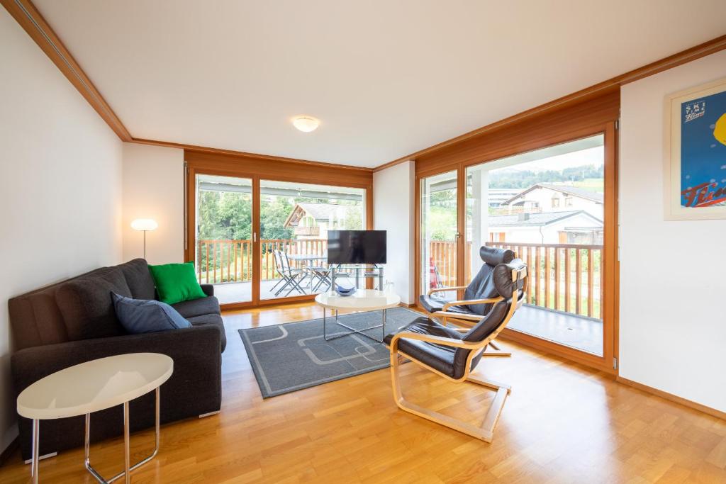 Una sala de estar con un sofá, una mesa y sillas. en LAAX Homes - Casa Miro Nr 7, en Flims