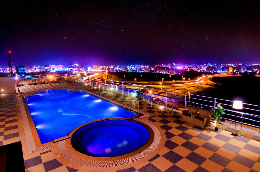 a swimming pool at night with a view of a city at Al Murooj Grand Hotel in Muscat