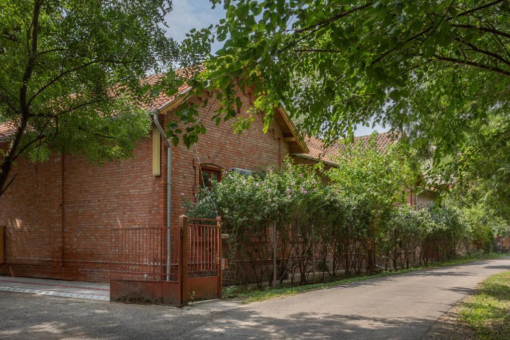 ein Backsteinhaus mit einem Zaun davor in der Unterkunft Pavilon Panzió Étterem és Pizzéria in Gyomaendrőd