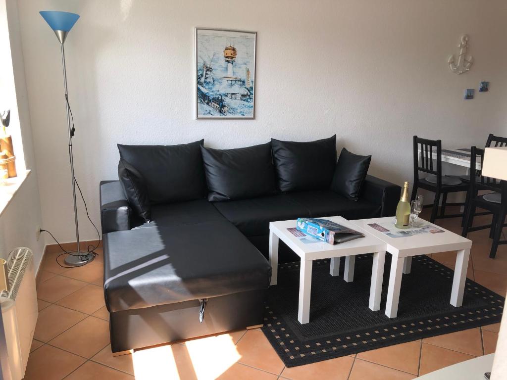 ein Wohnzimmer mit einem schwarzen Sofa und einem Tisch in der Unterkunft Ferienwohnung im Haus Sommerwind in Schönberger Strand