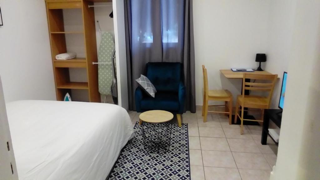 een slaapkamer met een bed, een stoel en een tafel bij Appartement AAD1 Clamart 200 m du Tramway T6 st pavé blc avec cuisine séparée in Clamart