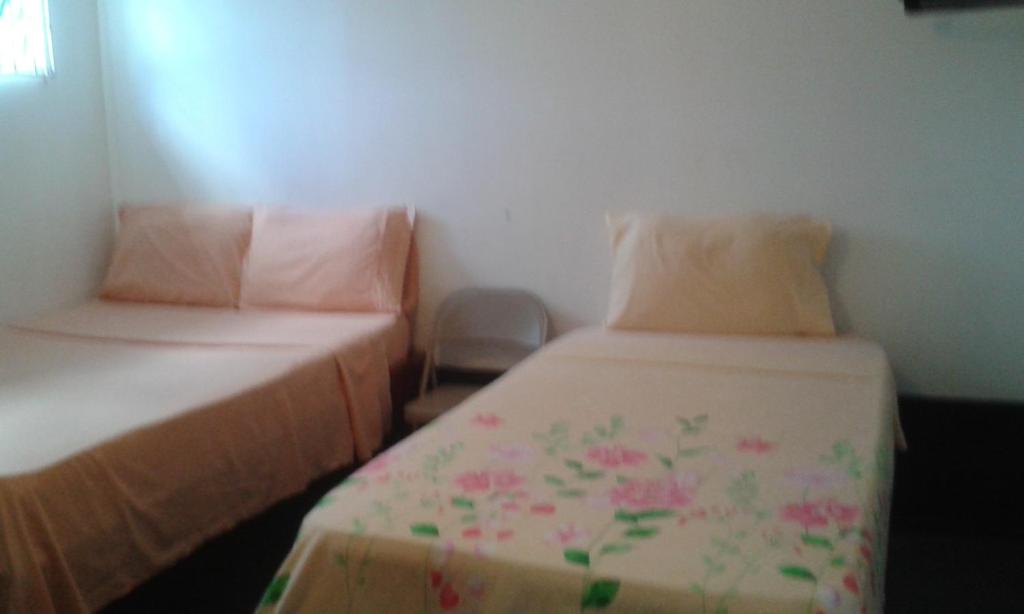 a bedroom with two beds with pink flowers on them at Drifters@One Mile in Negril
