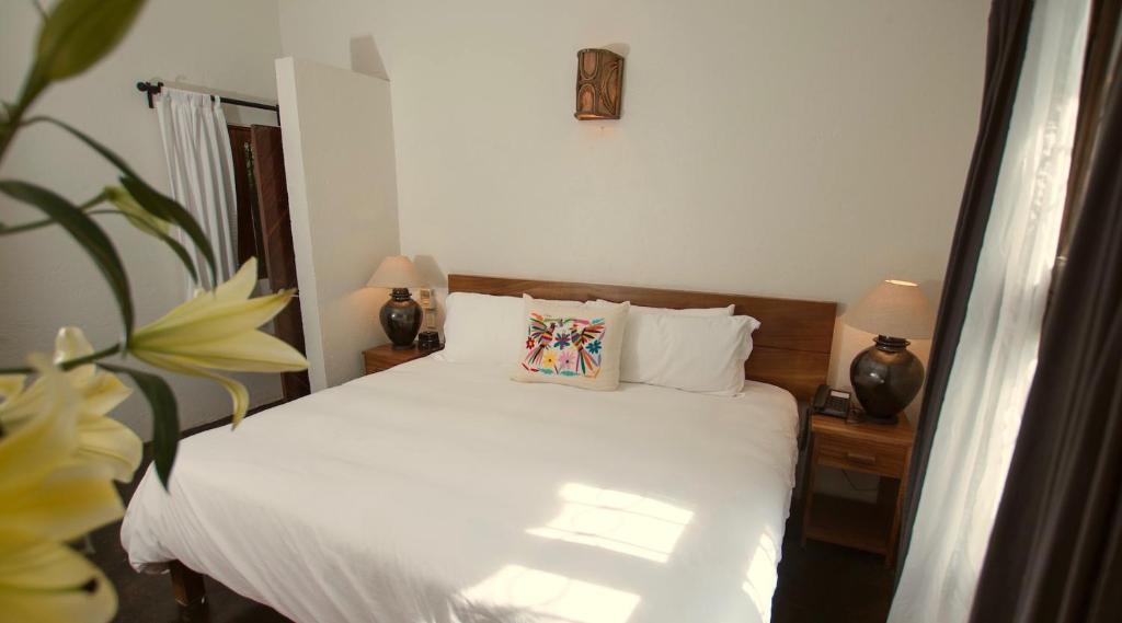 a bedroom with a bed with white sheets and two lamps at Villas Carrizalillo in Puerto Escondido