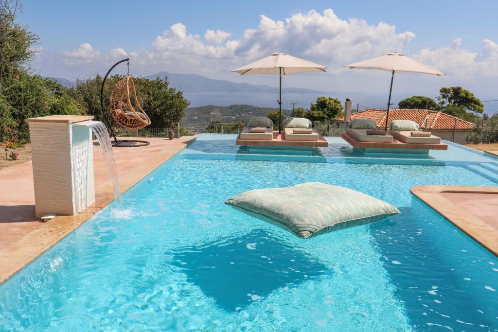einen Pool mit Kissen und Sonnenschirmen in der Unterkunft ANGIO VILLAS SPA in Skiathos-Stadt