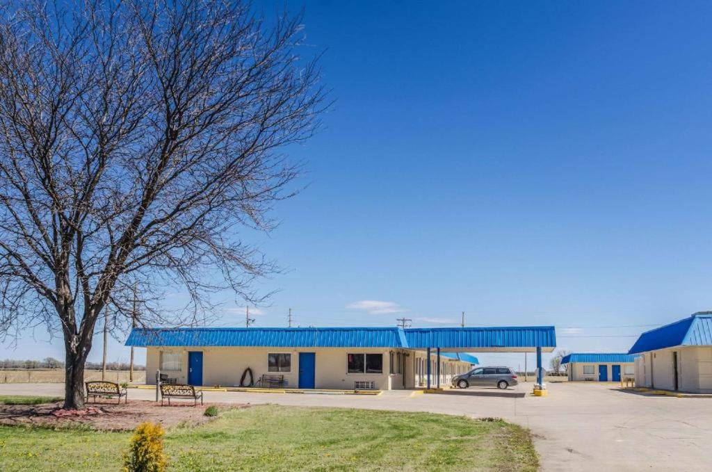 a building with a blue roof and a car in a parking lot at Regency Inn in Concordia