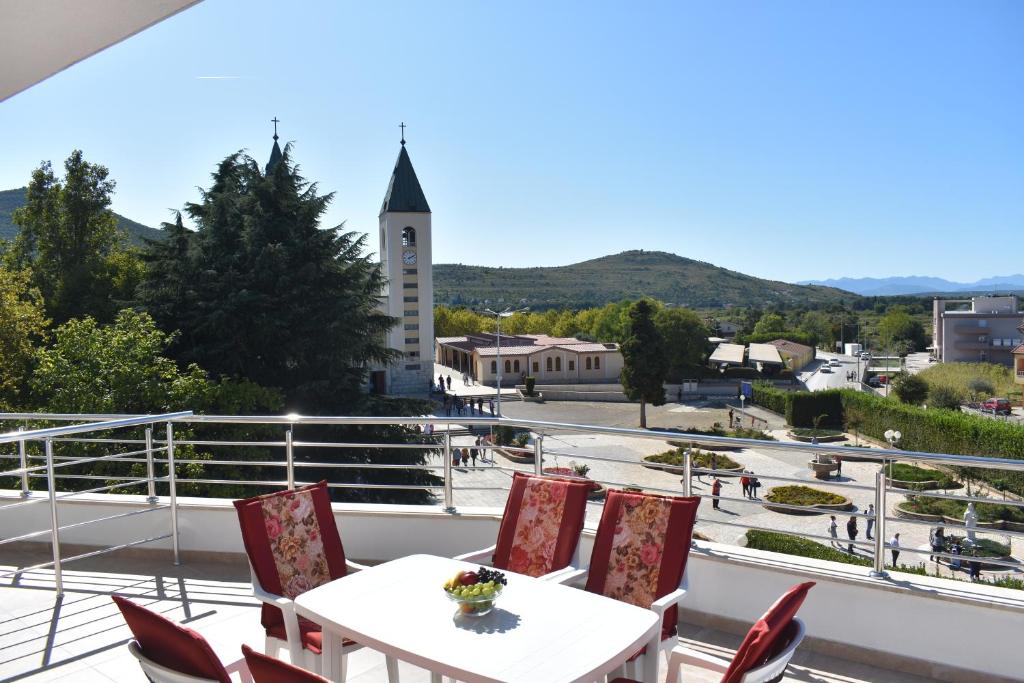 uma varanda com uma mesa e cadeiras e uma torre do relógio em Gloria Apartments 1 em Medjugorje