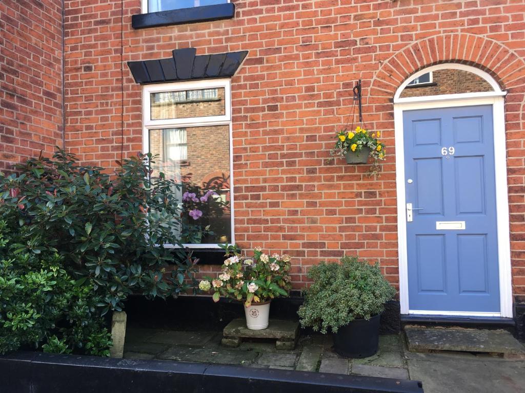 ceglany dom z niebieskimi drzwiami i roślinami w obiekcie La casa de Eloisa w mieście Macclesfield