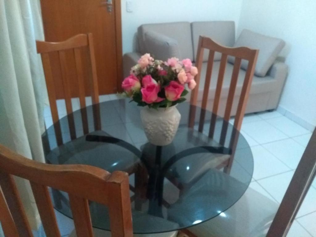 uma mesa de vidro com um vaso com flores cor-de-rosa em Claudia Apartment em Vila Velha