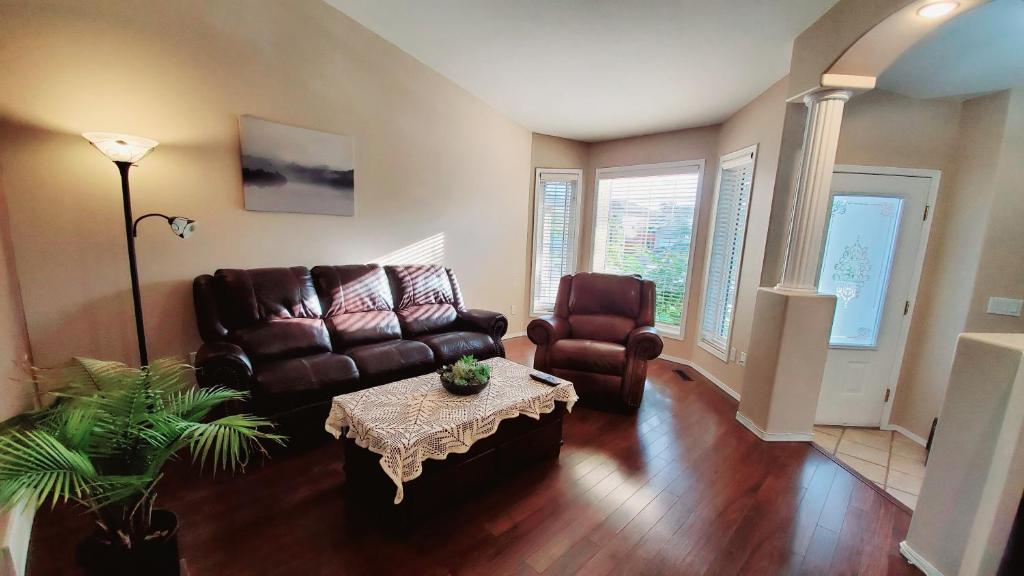 a living room with a leather couch and a table at Saskatoon Lashyn Cove Homestay in Saskatoon