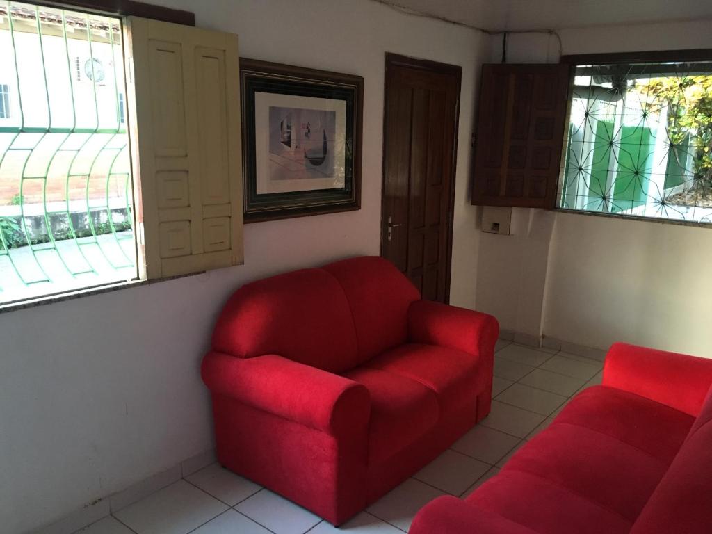 a red chair and a couch in a room at Hostel Manga Rosa in Santarém