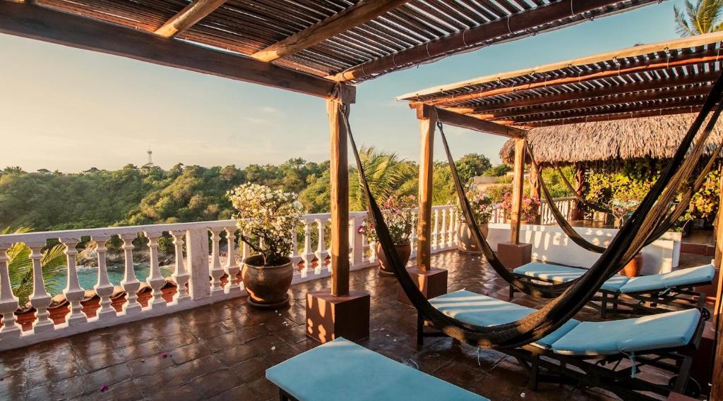 a porch with chairs and hammocks on a balcony at Villas Carrizalillo in Puerto Escondido