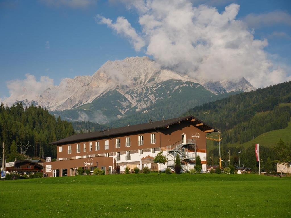 a building in a field in front of a mountain at Fairhotel Hochfilzen B&B in Hochfilzen