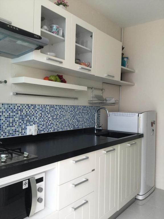 uma cozinha com armários brancos e um balcão preto em Best Point Condominium Cape Panwa em Cidade Phuket