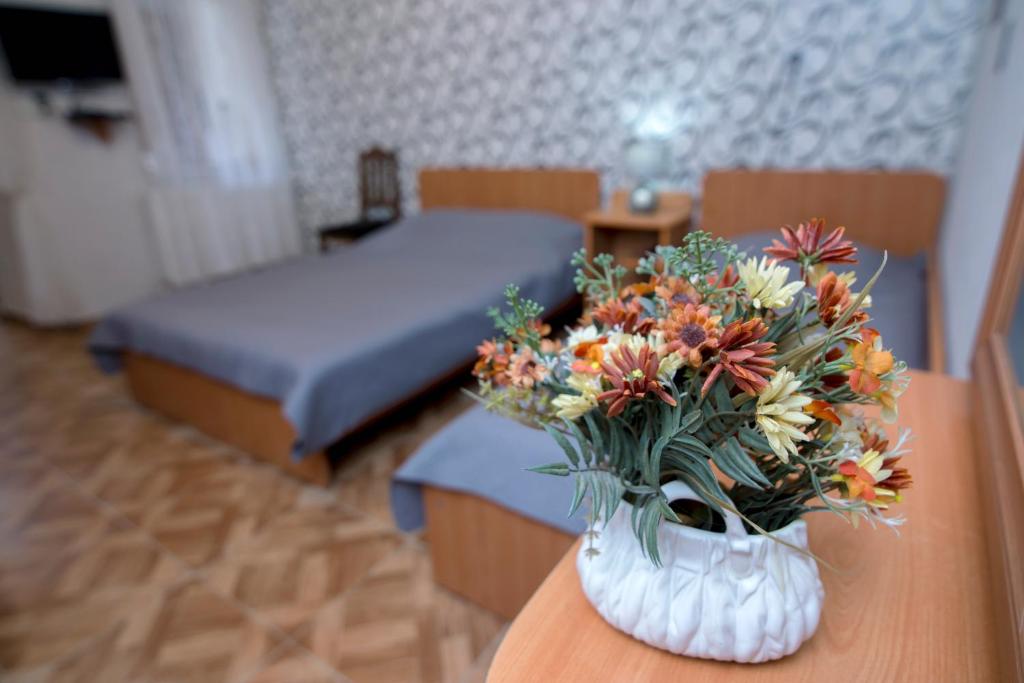 a vase of flowers on a table in a bedroom at Paata's Guesthouse in Borjomi