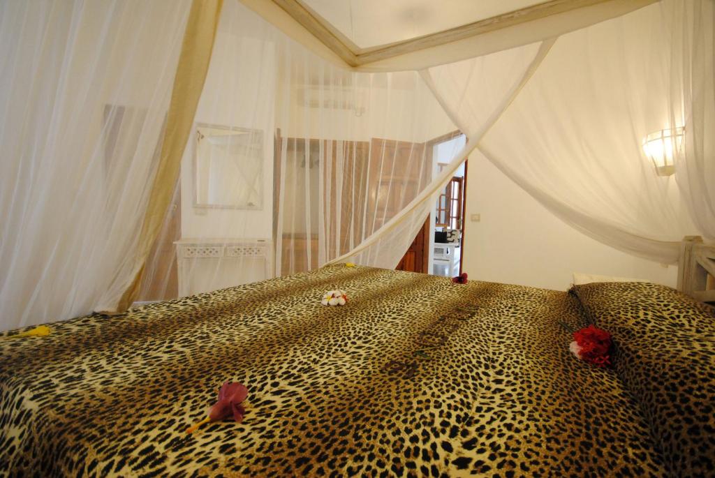 a bedroom with a leopard print bed with flowers on it at Kola Beach Resort in Mambrui