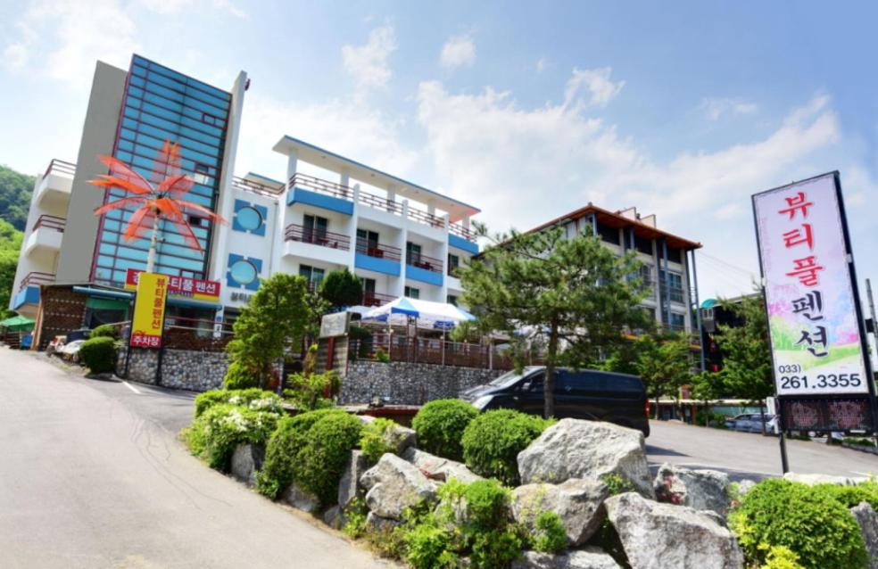 una calle con un edificio y algunos carteles y arbustos en Gangchon Beautiful Pension en Chuncheon