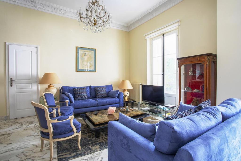 a living room with blue couches and a tv at Havre de paix au coeur de Cannes in Cannes