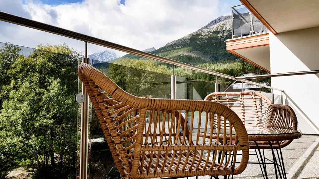 2 sillas de mimbre sentadas en un balcón con vistas a las montañas en Studio Hrebienok C211, en Starý Smokovec