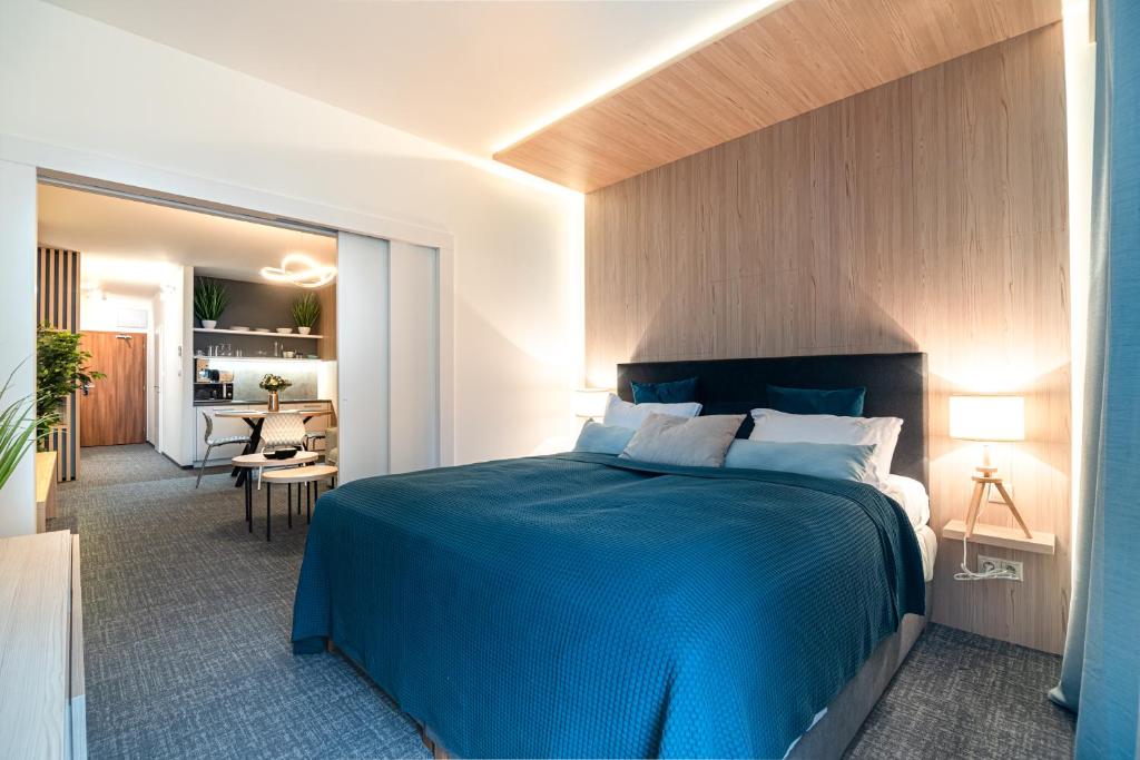 a bedroom with a blue bed and a living room at Apartman Pod Hrebienkom - C218 in Starý Smokovec
