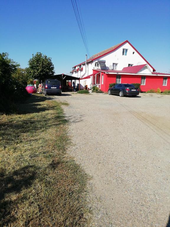 a red and white house with cars parked in the driveway at Pensiunea Mario in Curtici