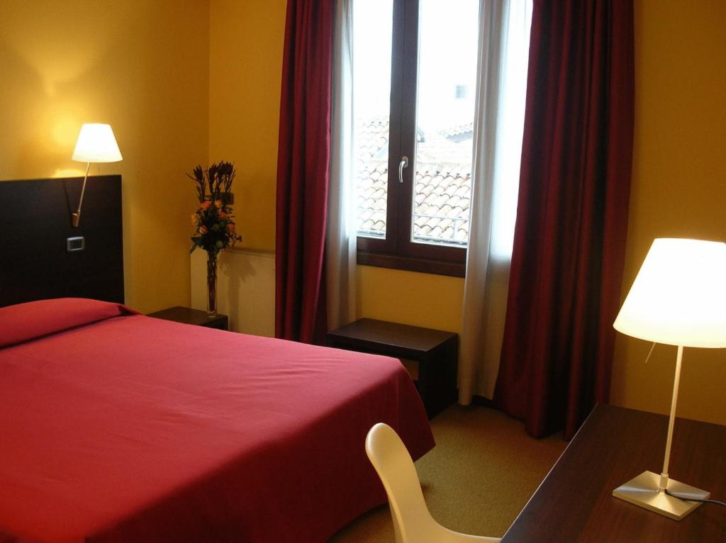 a hotel room with a red bed and a window at Albergo Verdi in Padova