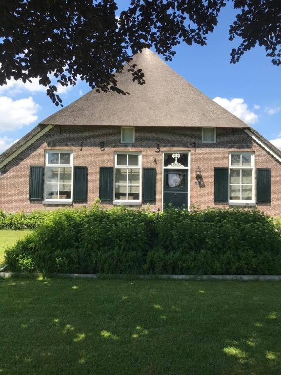 a brick house with a clock in the window at B&B “de Boerlarij” in Ruinerwold