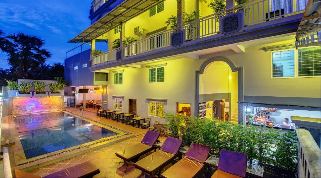 a building with chairs and a swimming pool at night at Siem Reap Pub Hostel in Siem Reap