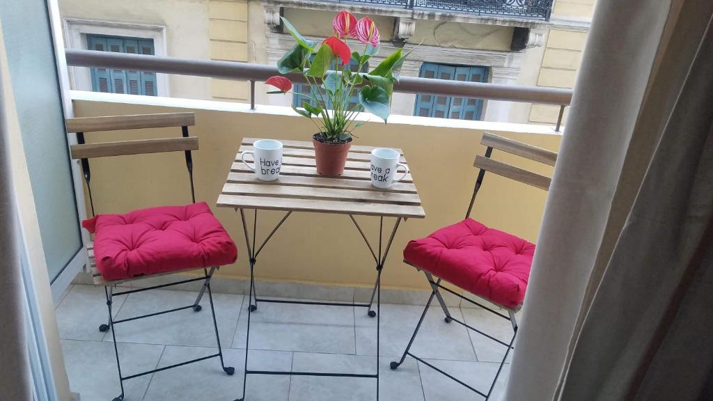 einen Tisch und zwei Stühle auf einem Balkon mit Fenster in der Unterkunft Yolanda Studios in Piräus