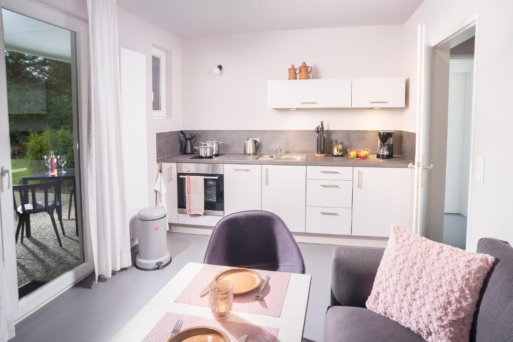 a kitchen with white cabinets and a table and chairs at NordseeHeide-Lodges Cuxhaven in Cuxhaven