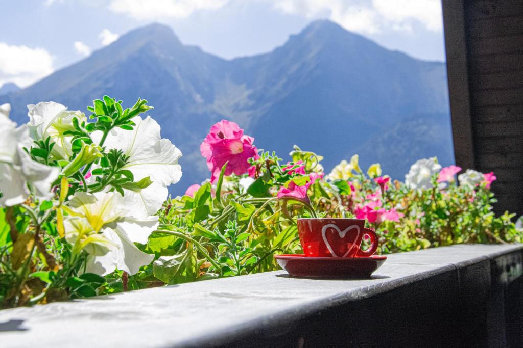 a red cup sitting on a table with flowers at Chalupa Chalet Strachan in Ždiar