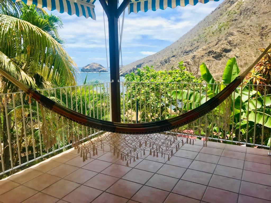 a hammock on a balcony with a view of the ocean at Villa Figues et Mangos in Terre-de-Haut
