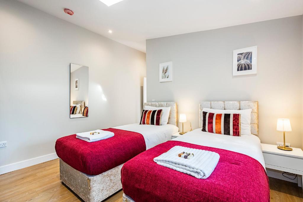 - 2 lits dans une chambre avec des couvertures rouges dans l'établissement South Woodford 2 Bed En-Suite House, à Londres