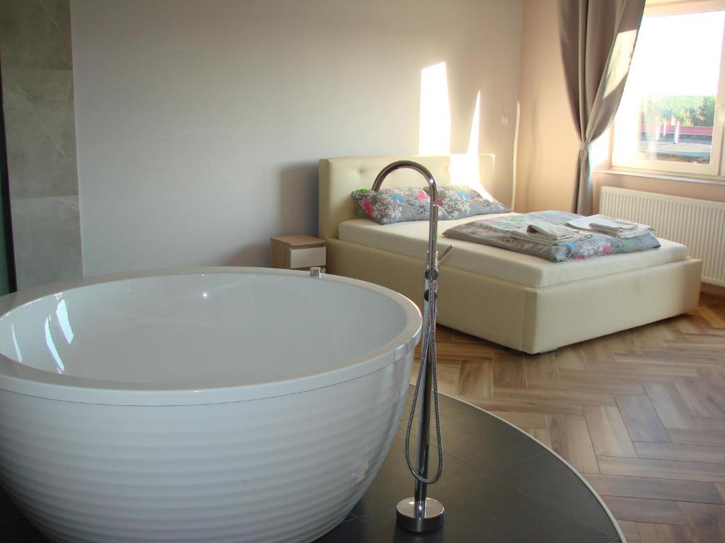 a bathroom with a bath tub and a bed at Pensjonat Lubianka in Starachowice