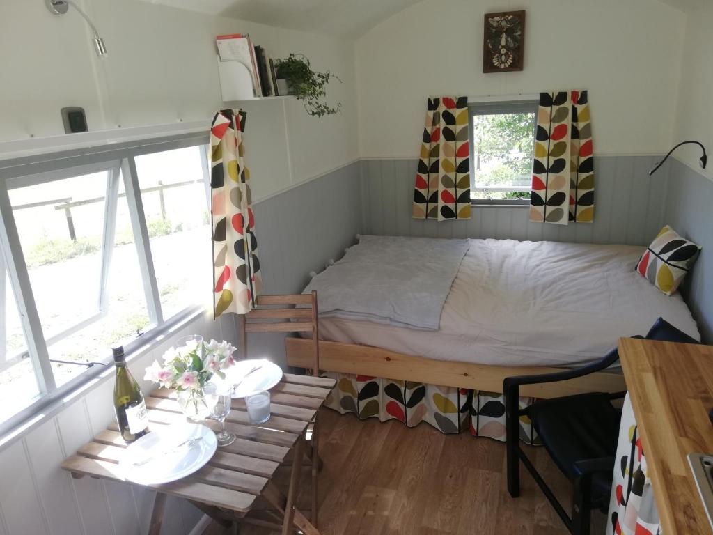 a small room with a bed and a table at The Hut at Downlands in Warminster