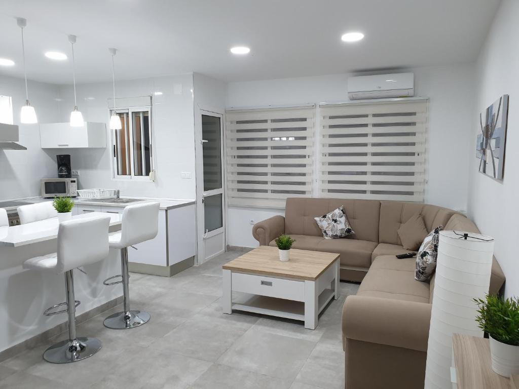 ein Wohnzimmer und eine Küche mit einem Sofa und einem Tisch in der Unterkunft Centre Apartment near Plaza de Toros in Alicante