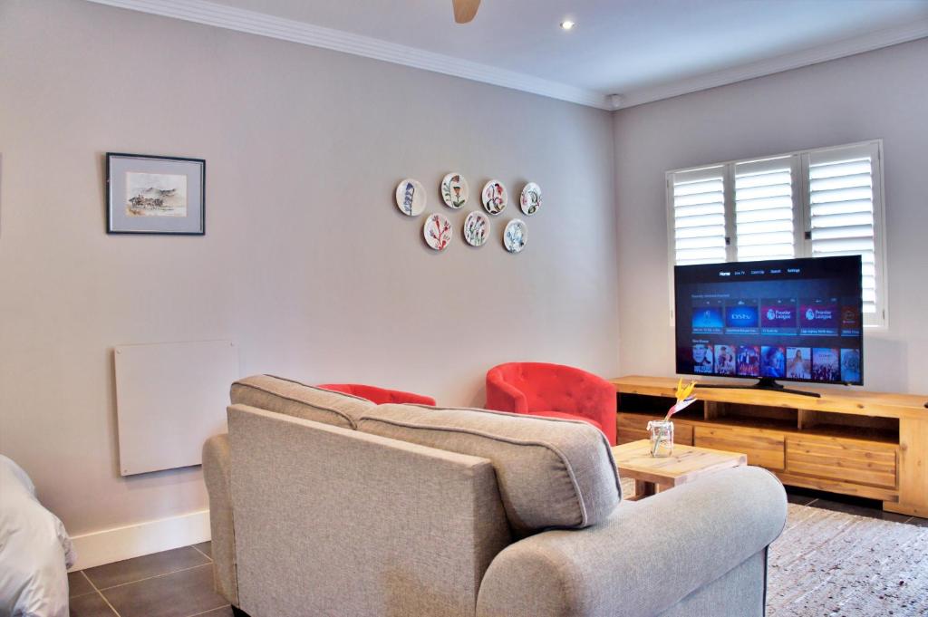 a living room with a couch and a tv at The Cottage 60 on 21st Avenue in Mossel Bay